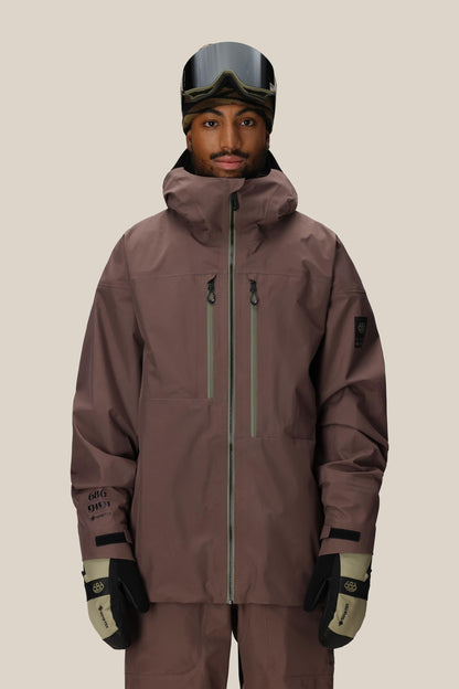 Person wearing a 686 GORE-TEX 3L ATV Thermagraph® Jacket 1 snow jacket, pants, and goggles on a beige background.