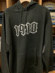 Black hoodie with white 1910 logo on a wooden surface