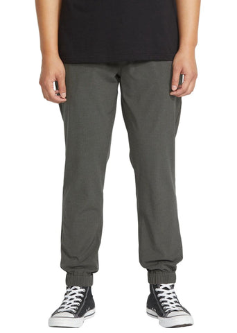 Person wearing Volcom joggers and black sneakers on a white background